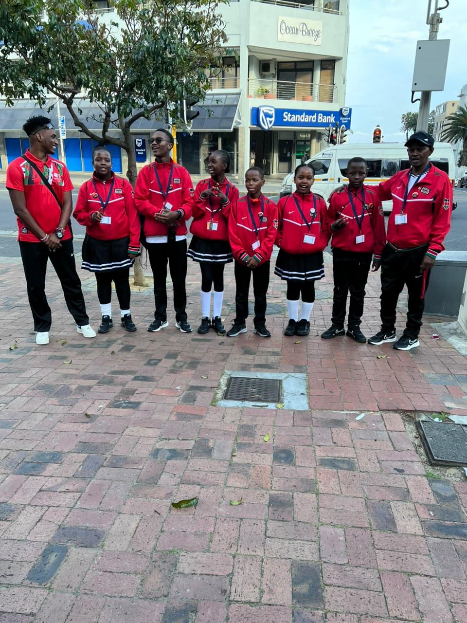 Kenya team members in red tracksuits posing together on a city street