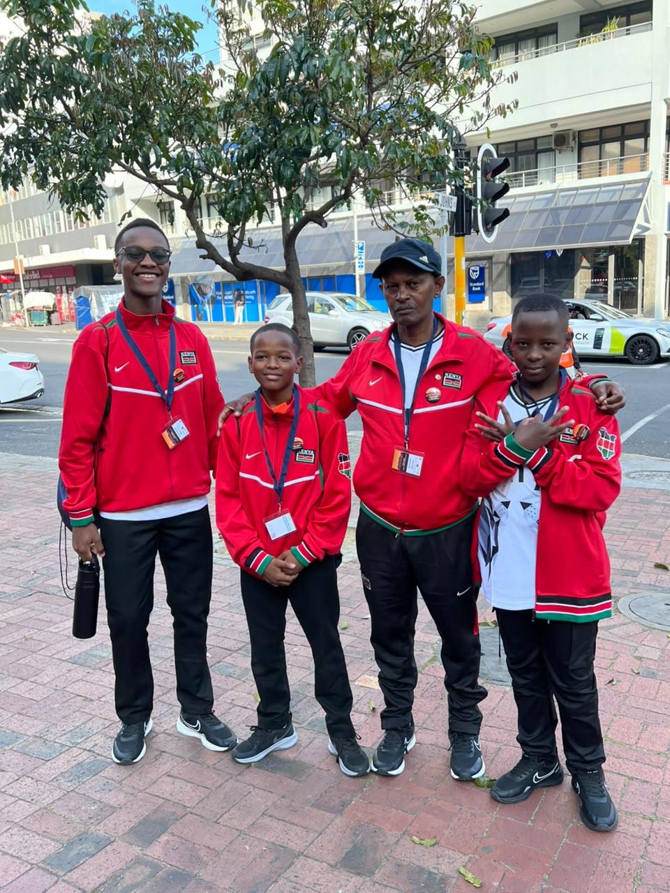 Kenya cubers and coaches posing together in red team tracksuits